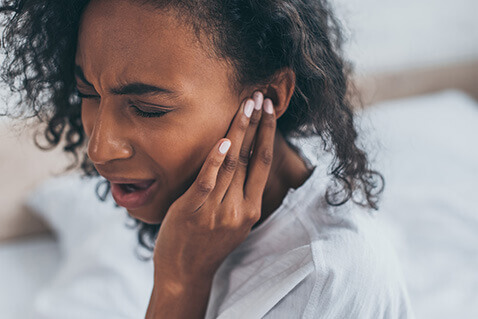 Young woman with ear pain or tinnitus